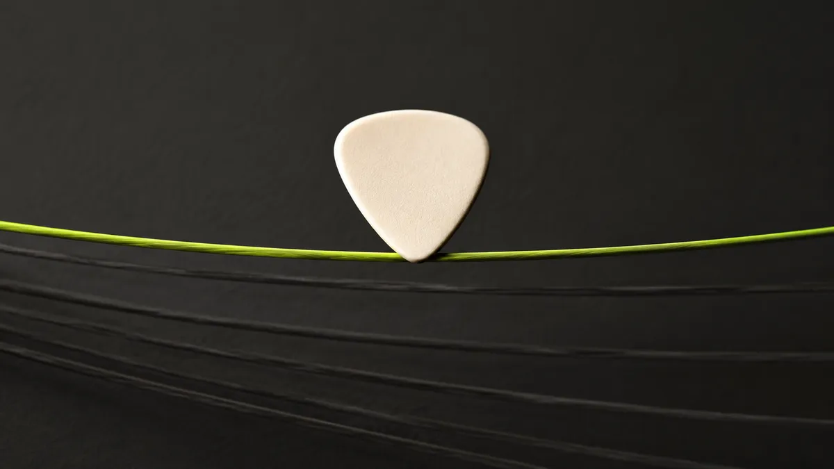 A single guitar pick and string in a spacious composition